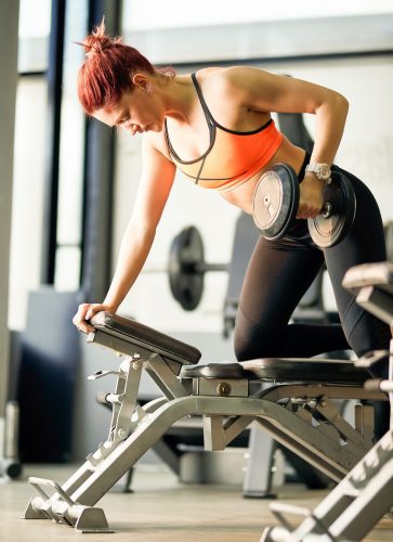 Athletische Frau trainiert an Kurzhantelbank mit Gewicht